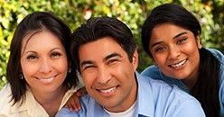 Family of three smiling outdoors