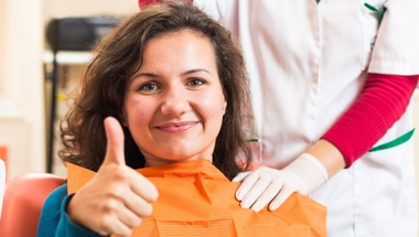 Woman in dental chair giving thumbs up