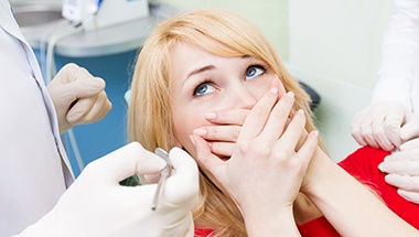 Woman in dental chair covering mouth