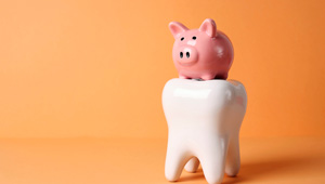 Pink piggy bank on large model tooth with orange background