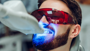 Man undergoing teeth whitening at dental office