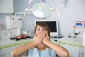 A woman covering her mouth at the dental office.