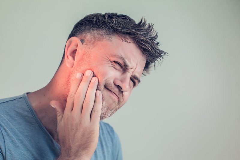 Man with dental insurance holding his mouth in pain