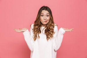 woman shrugging trying to decide between root canal and tooth extraction