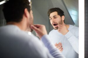 Man checking his swollen gums in the mirror