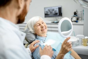 a senior woman smiling as she gets her teeth taken care of by her dentist