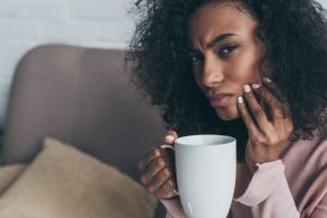 woman with tooth sensitivity drinking coffee