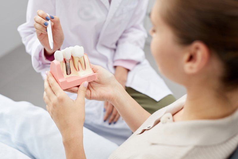 A patient holding a dental implant model