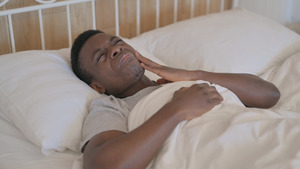 Patient lying in bed and holding their cheek