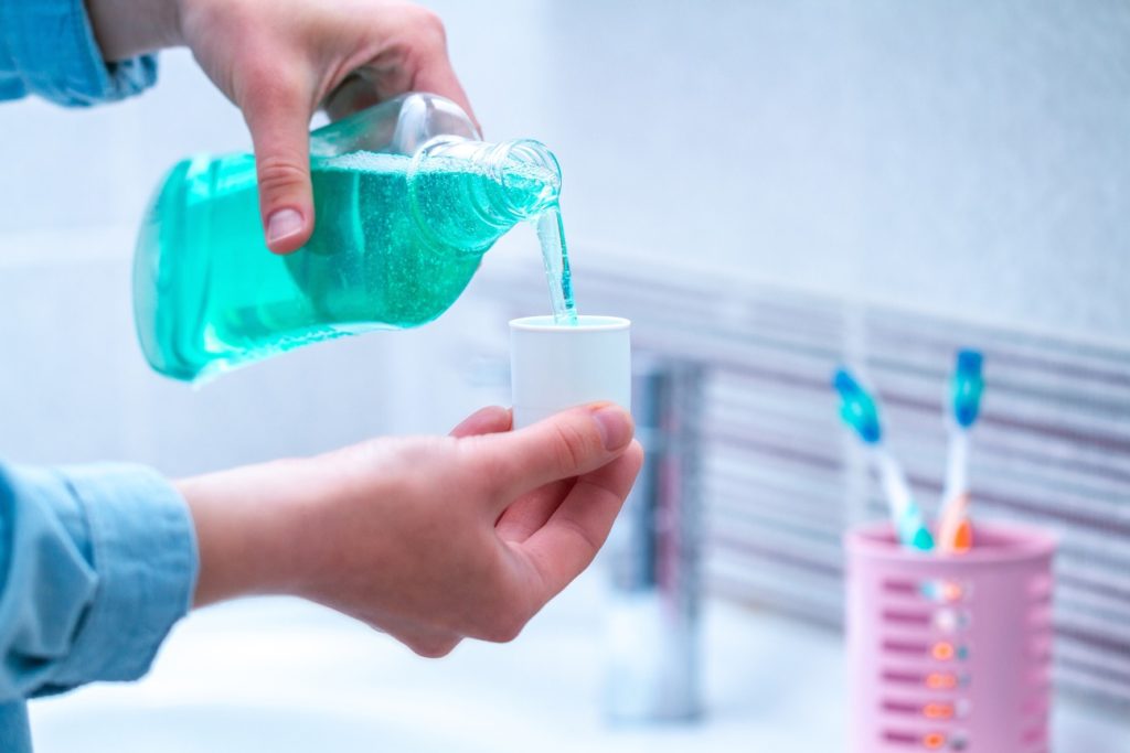 Someone pouring mouthwash into a cup on advice from a dentist