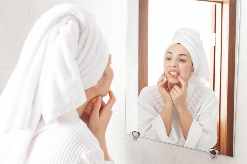 Woman checking her teeth and gums in mirror