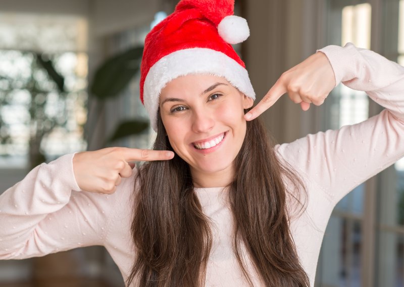 Woman in Santa hat pointing at her smile