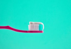 Toothbrush with toothpaste against a green background.